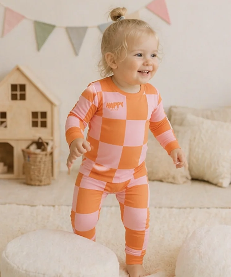 A smiling toddler in Sunset Pop bamboo pajamas